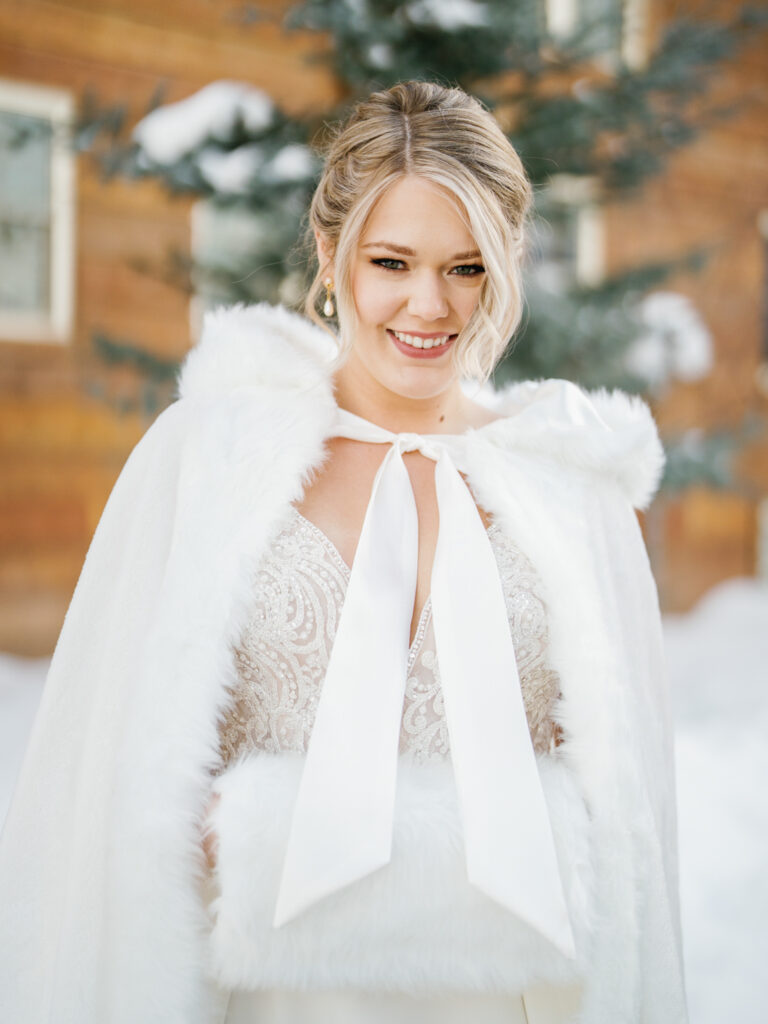 A cozy winter bride in front of Sun Valley Lodge in the snow before wedding.