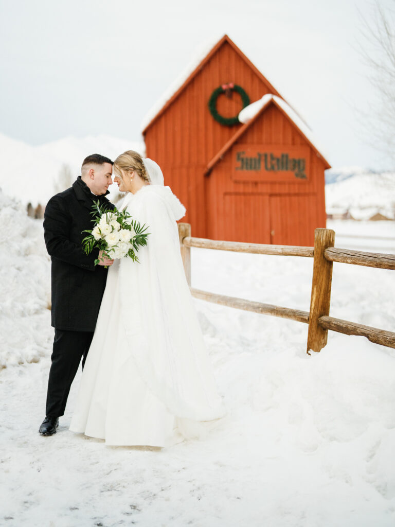 Newlyweds in a Winter Wonderland Sun Valley Wedding in front of the red barn.