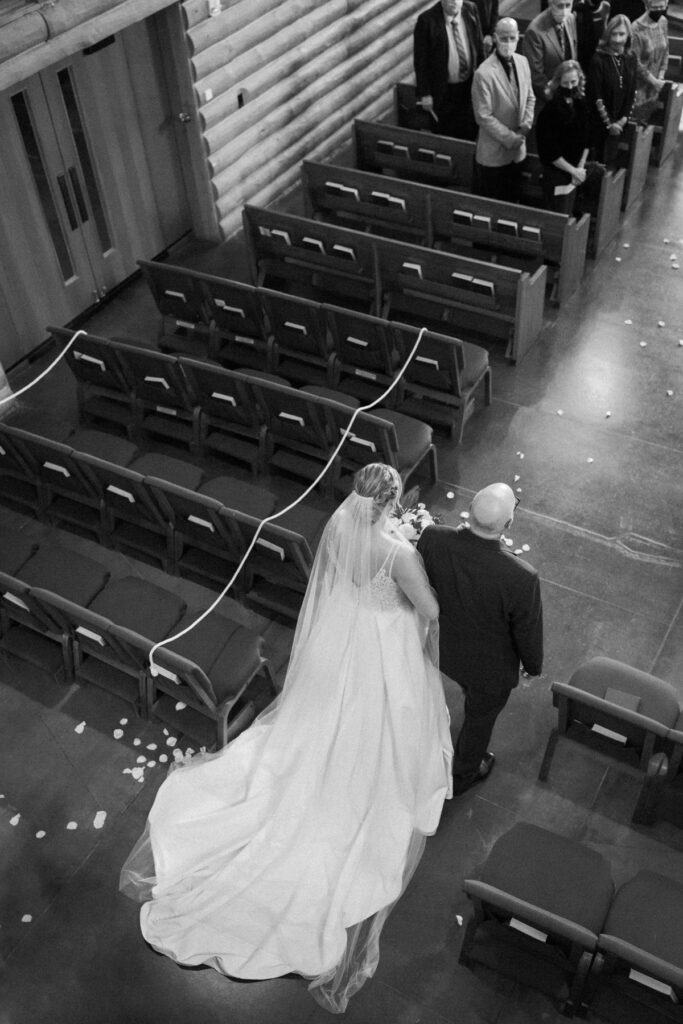 Bride walking down aisle during ceremony at Saint Thomas Episcopal Church in Sun Valley